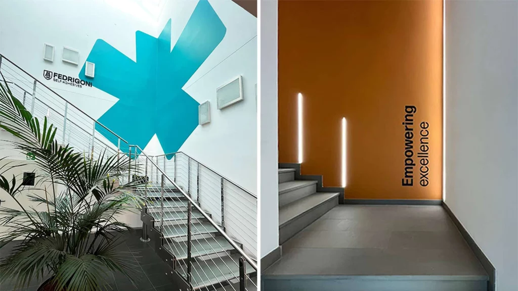 Doppia foto di un ingresso aziendale moderno con scale: a sinistra, grande logo Fedrigoni blu e piante; a destra, parete arancione con scritta "Empowering excellence" illuminata da strisce LED verticali, ideale per insegne luminose da interno.